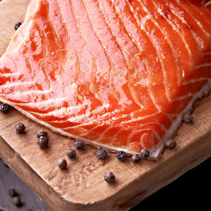 Fresh salmon fillet on a wooden board with peppercorns.