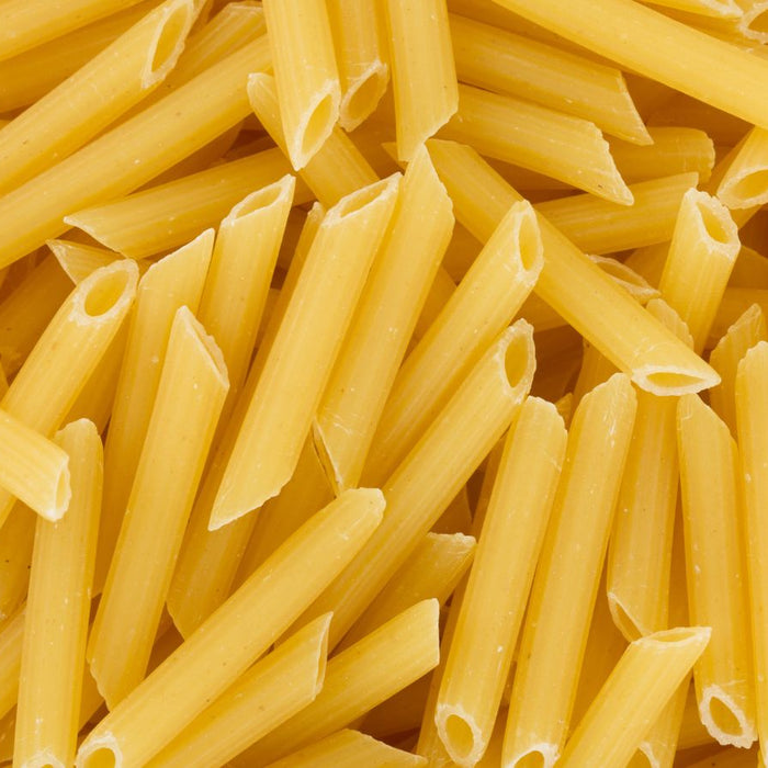 Dry penne pasta pieces in a full-frame close-up overhead view.