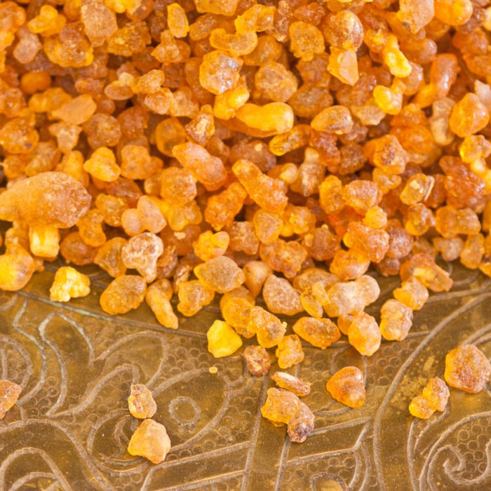 Frankincense resin granules on an ornate golden tray.