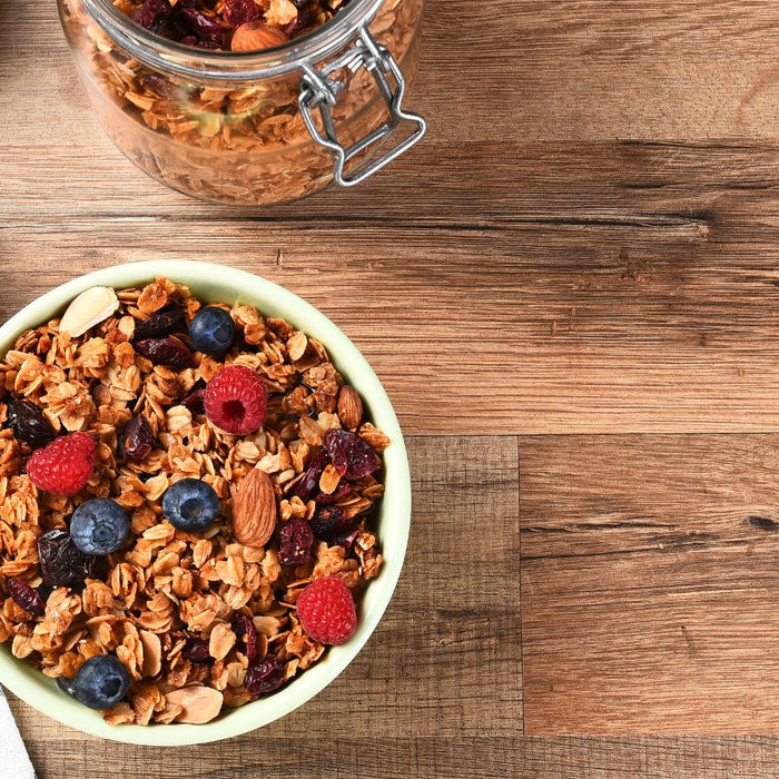 Granola cereal with berries and almonds in a bowl on wooden table.