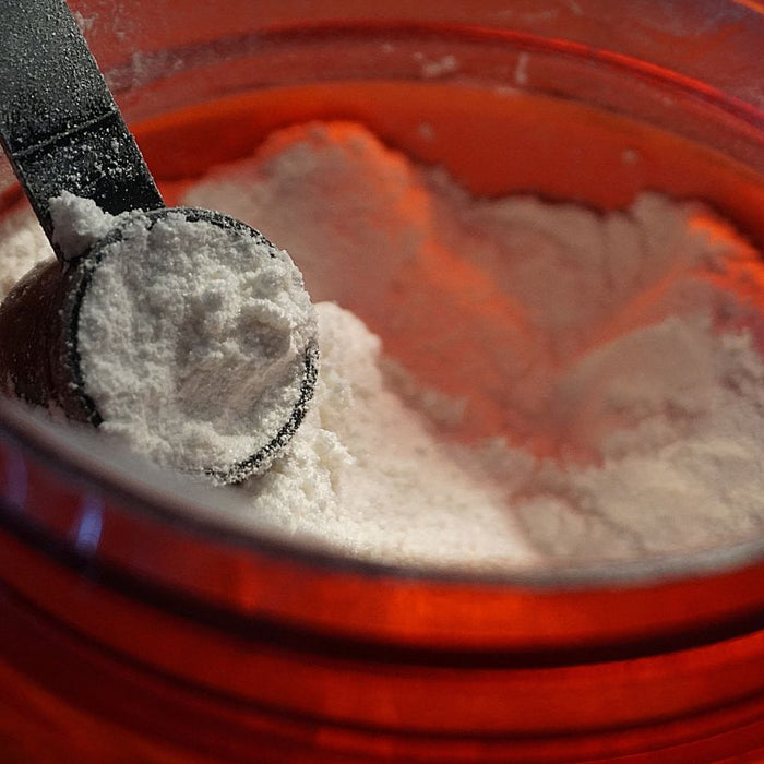 Protein powder in a red container with a black scoop.