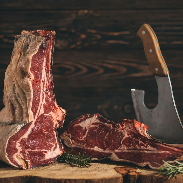 Raw wagyu beef with a cleaver on a wooden chopping block.