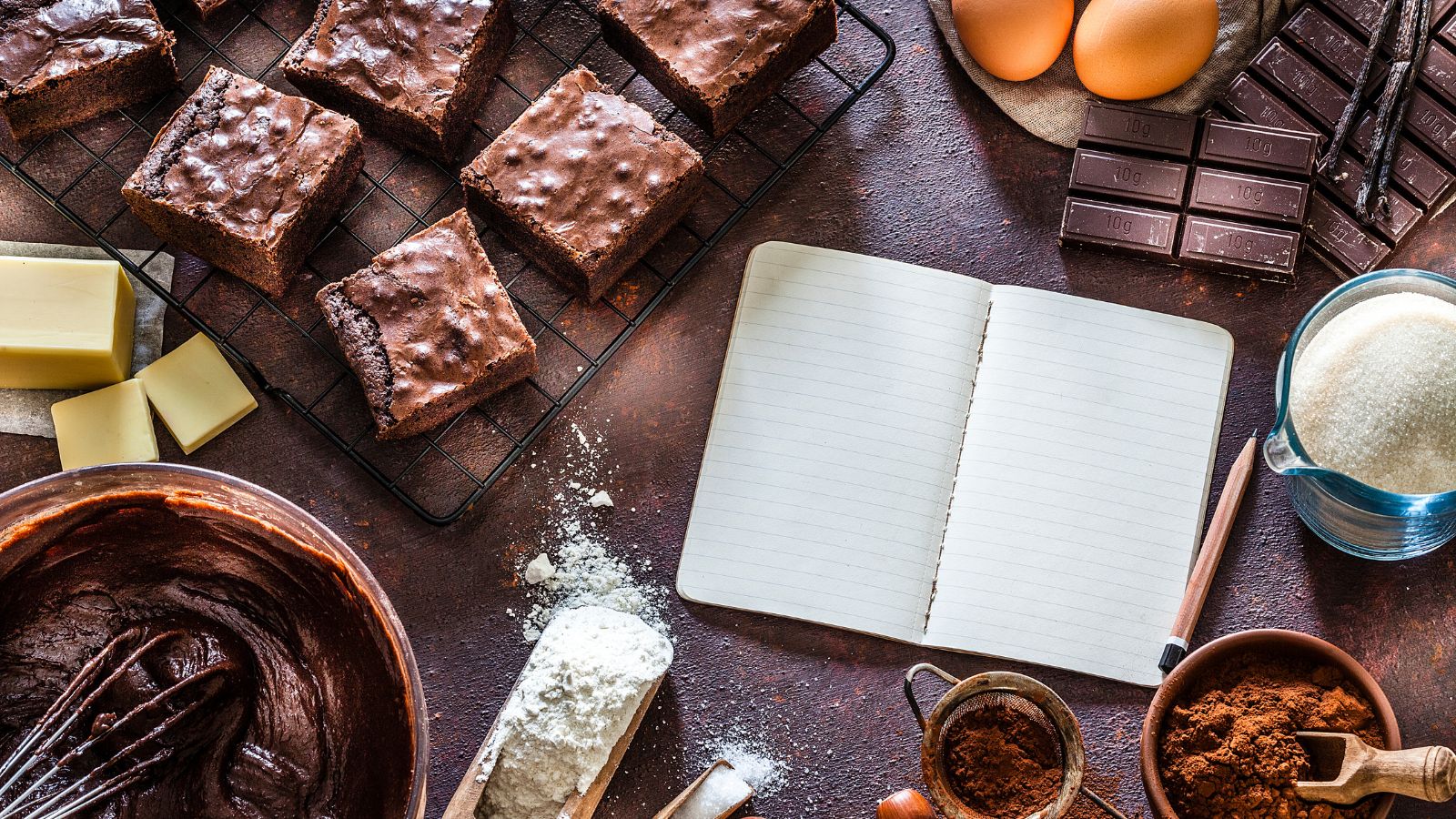 Freshly baked brownies cooling on a rack with baking ingredients around