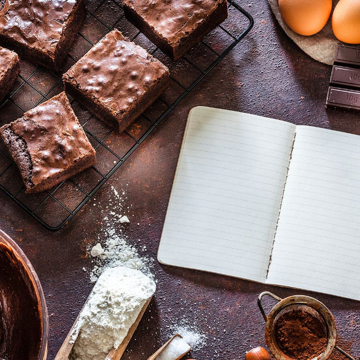 Freshly baked brownies cooling on a rack with baking ingredients around