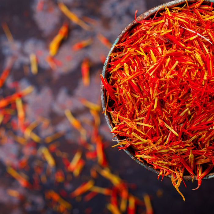 Bowl of vibrant red saffron threads on dark background.
