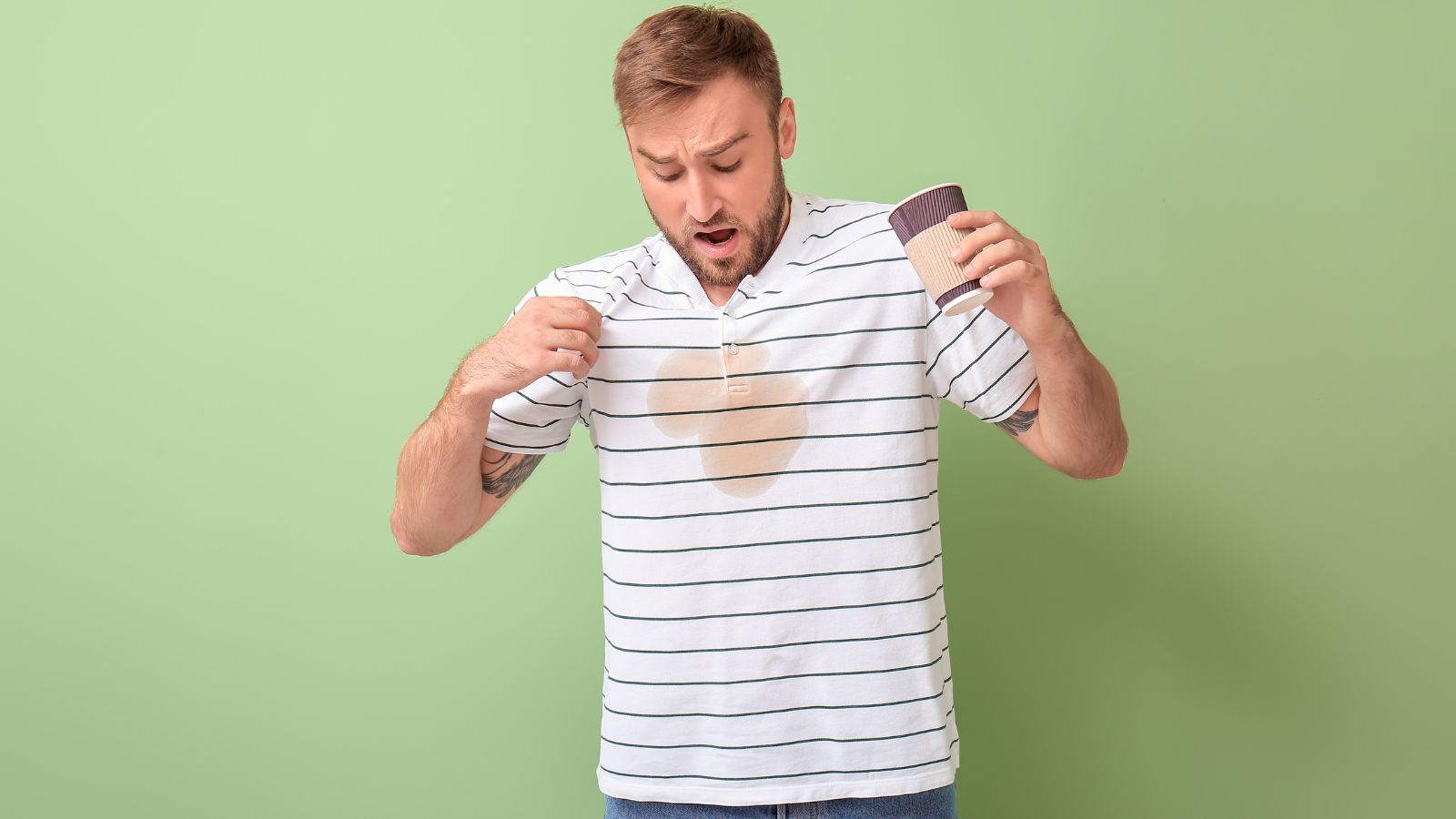 Man shocked by turmeric stain on white shirt against green background