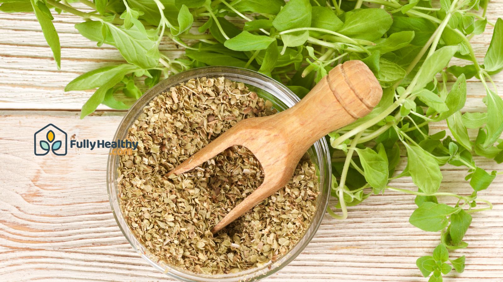 Dried oregano in bowl with fresh herbs on wooden background.