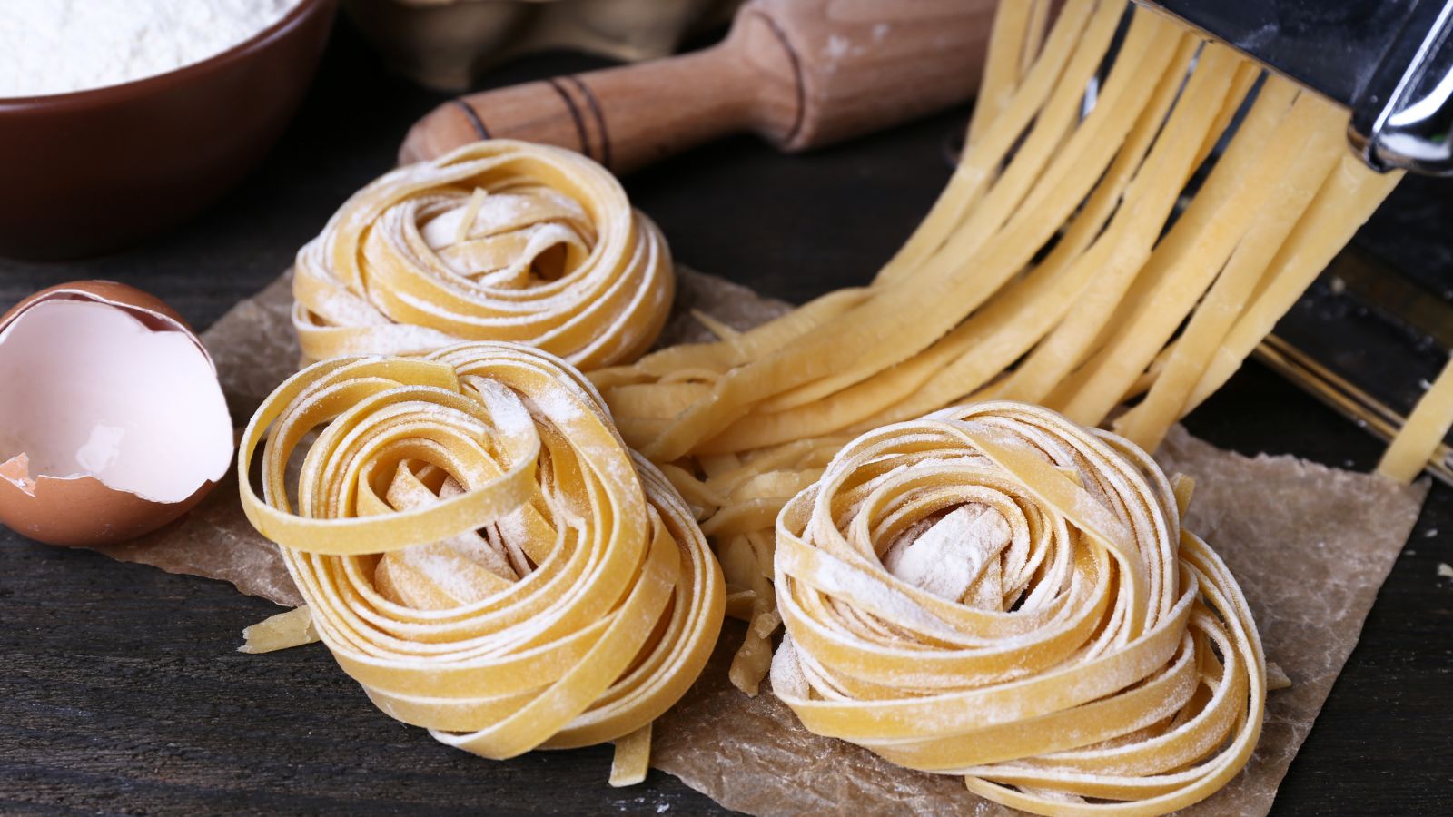 Rustic kitchen scene with fresh spaghetti pasta dough, flour, and egg shells