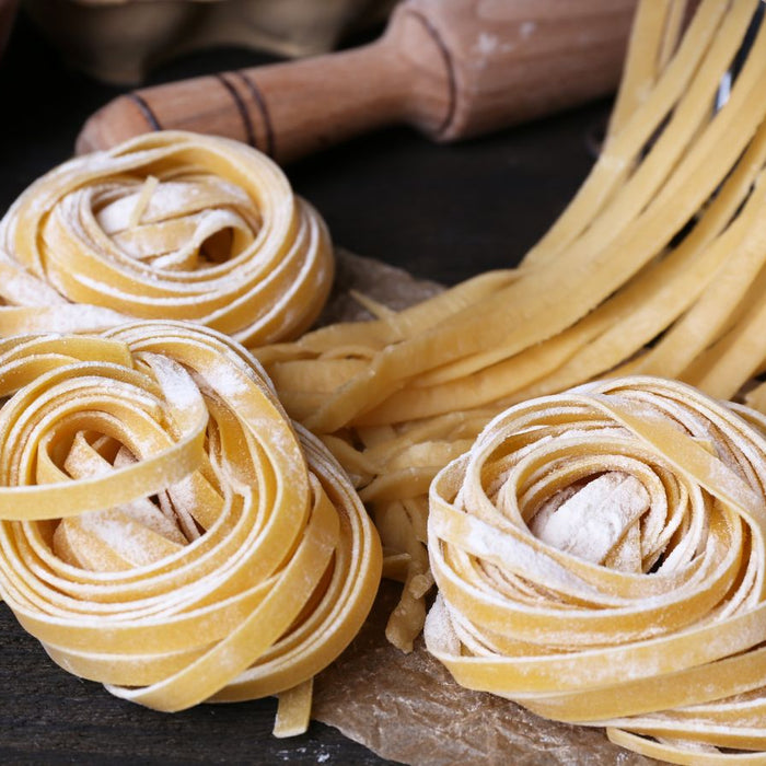 Rustic kitchen scene with fresh spaghetti pasta dough, flour, and egg shells
