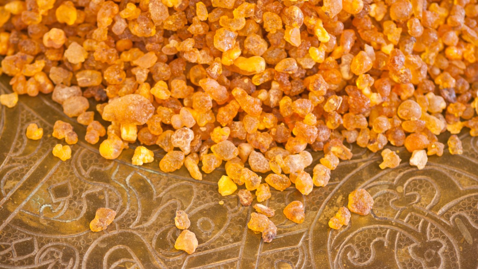 Frankincense resin granules on an ornate golden tray.