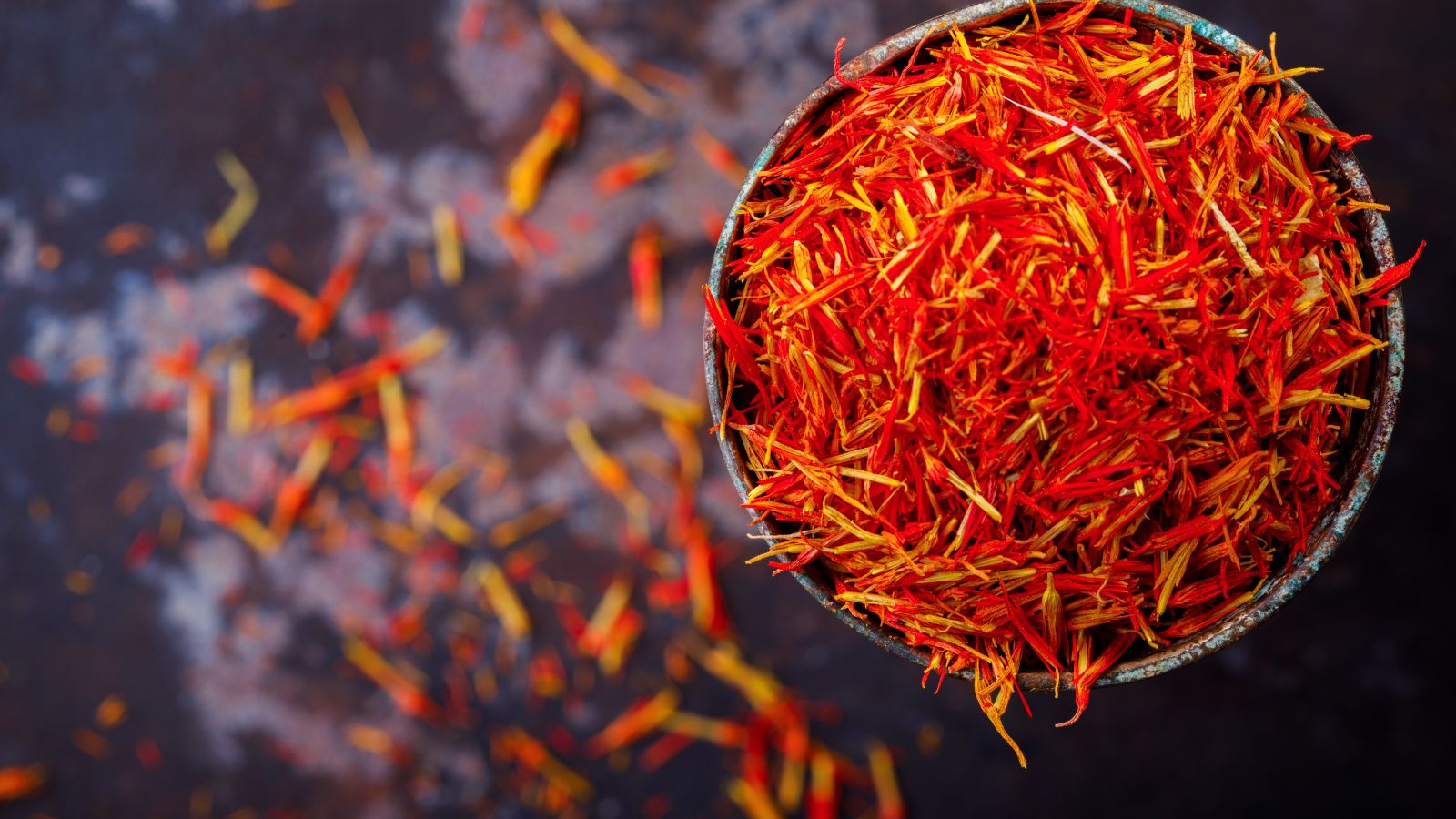 Bowl of vibrant red saffron threads on dark background.