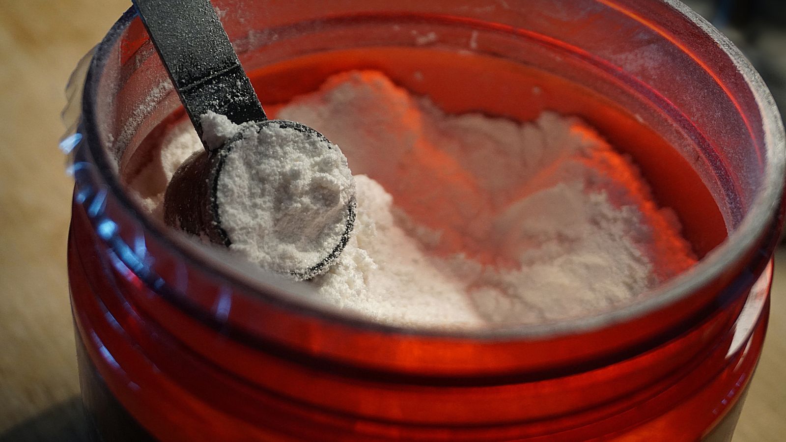Protein powder in a red container with a black scoop.