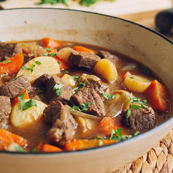 Hearty beef stew with carrots and potatoes served in a white casserole