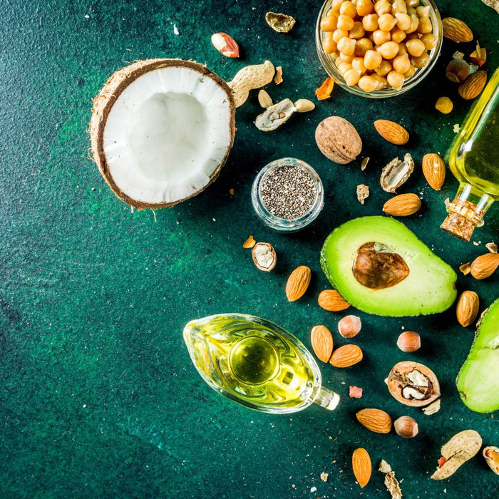 Healthy fats with avocado, coconut, nuts, and chia seeds on table