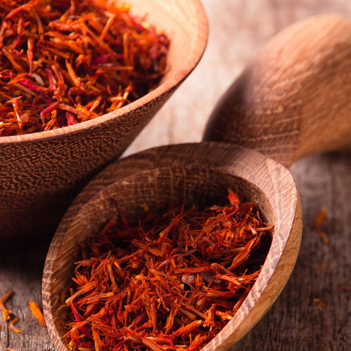 Dried saffron threads in a wooden bowl on a rustic wooden table.