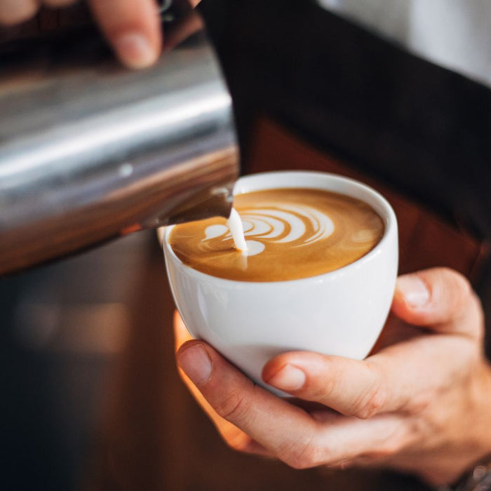 Latte art in progress with milk being poured into coffee