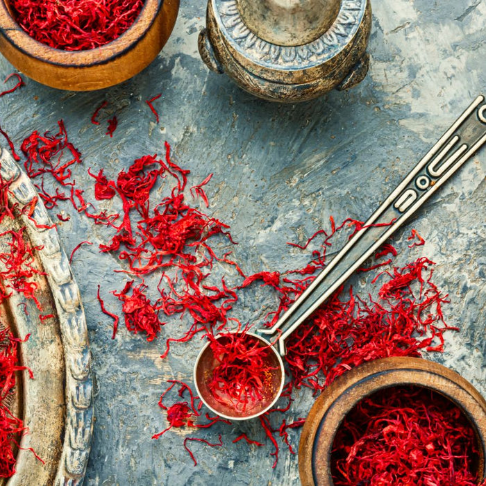 Loose saffron threads on a tray with vintage spice tools around.