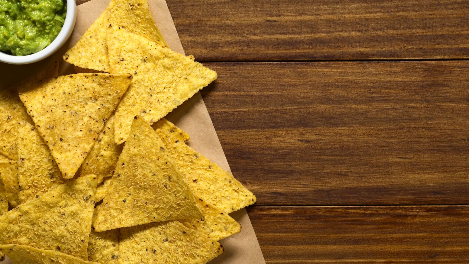 Crispy tortilla chips served with a bowl of green guacamole dip