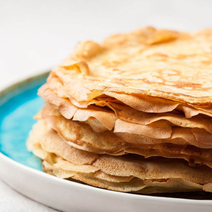 Stack of golden brown crepes on a blue plate ready to be served