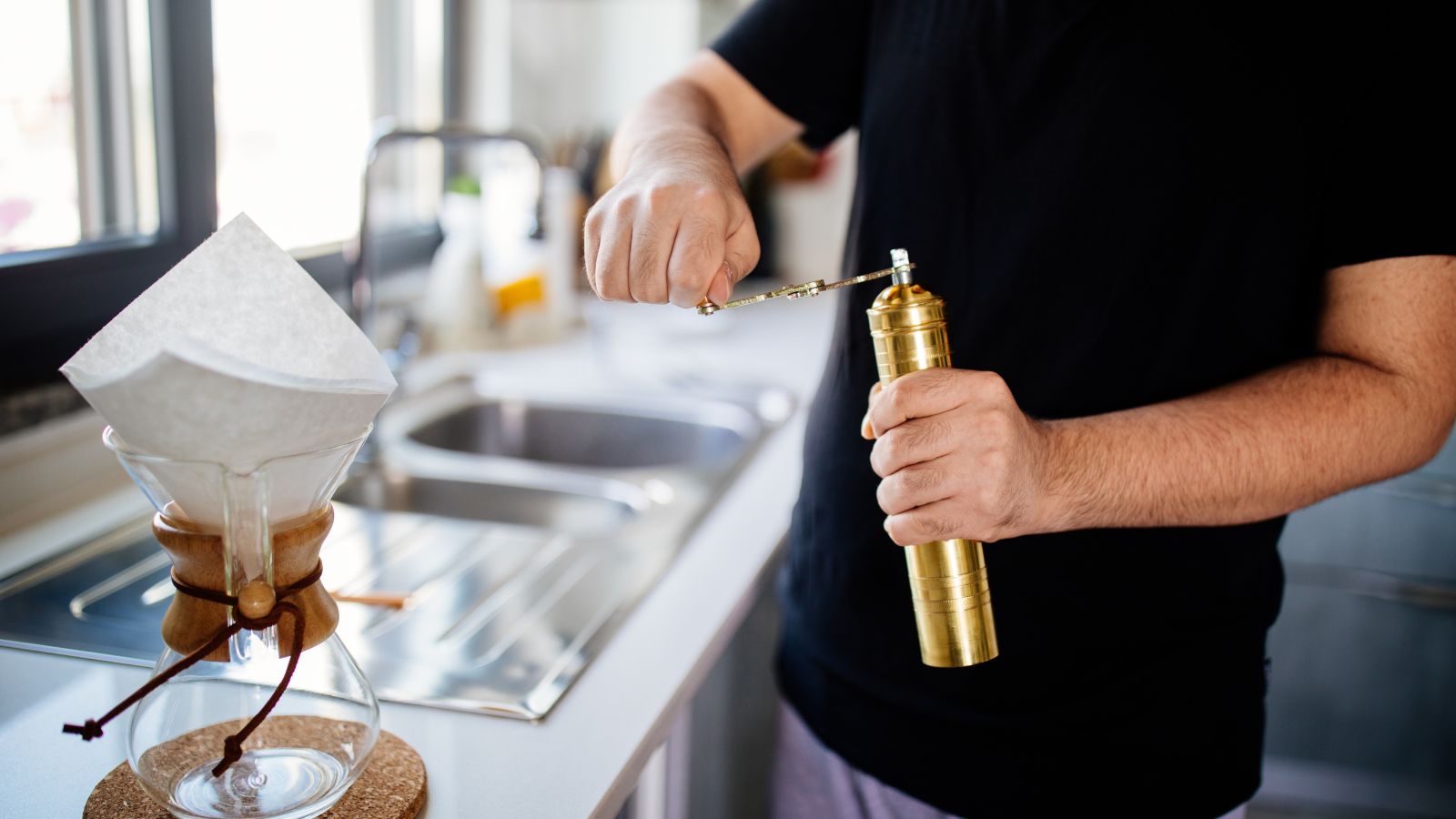 Man preparing coffee using a manual grinder and pour-over setup