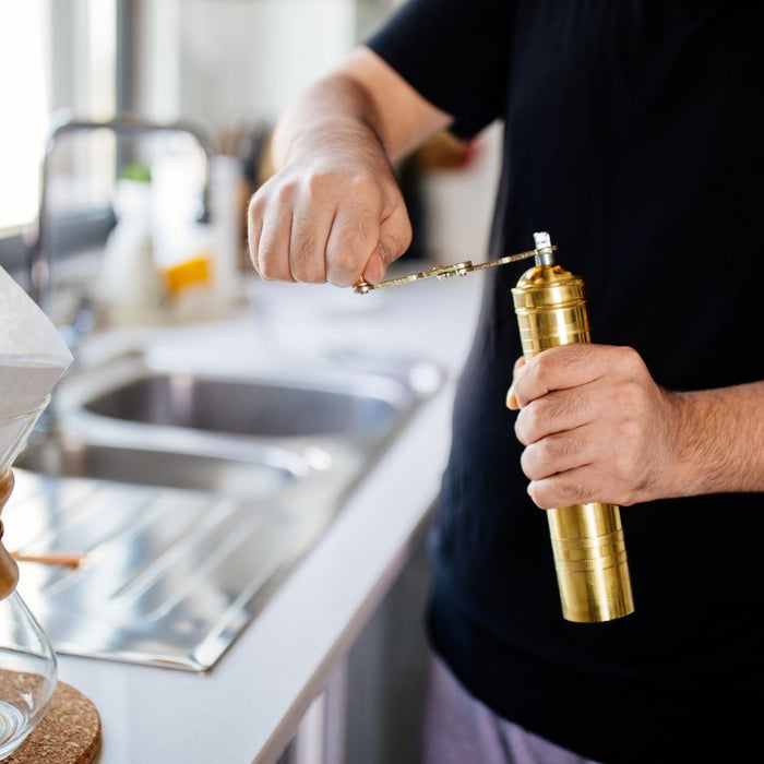 Man preparing coffee using a manual grinder and pour-over setup