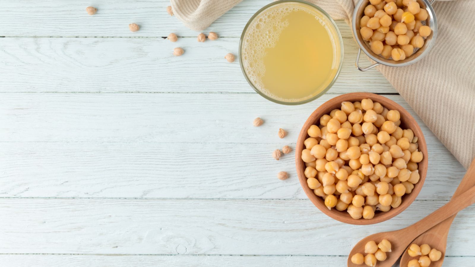 Bowl of chickpeas with aquafaba juice on rustic white wooden table