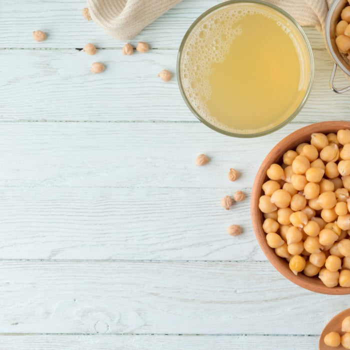 Bowl of chickpeas with aquafaba juice on rustic white wooden table
