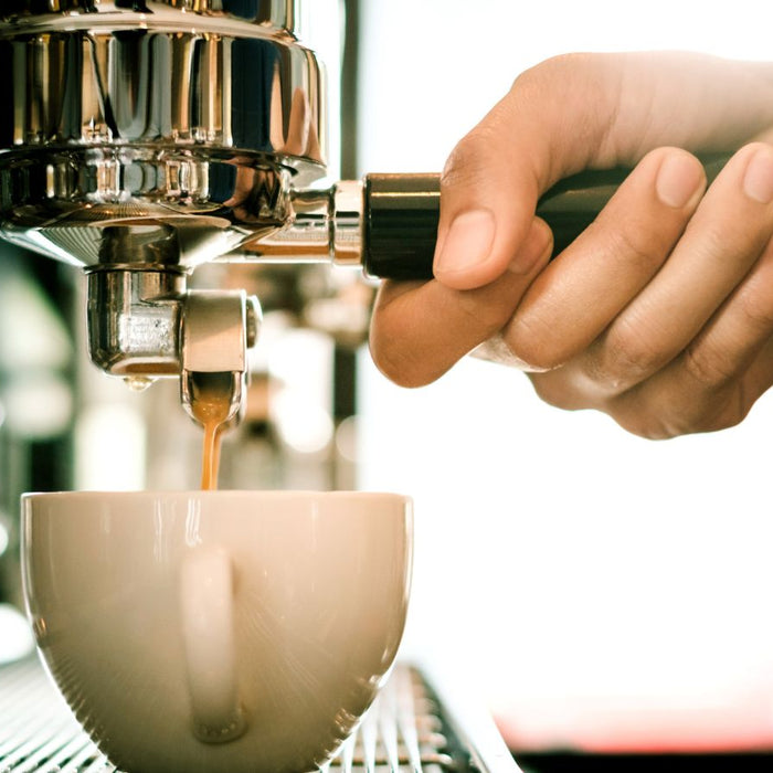 Barista pulling espresso into a cup with tattooed hand