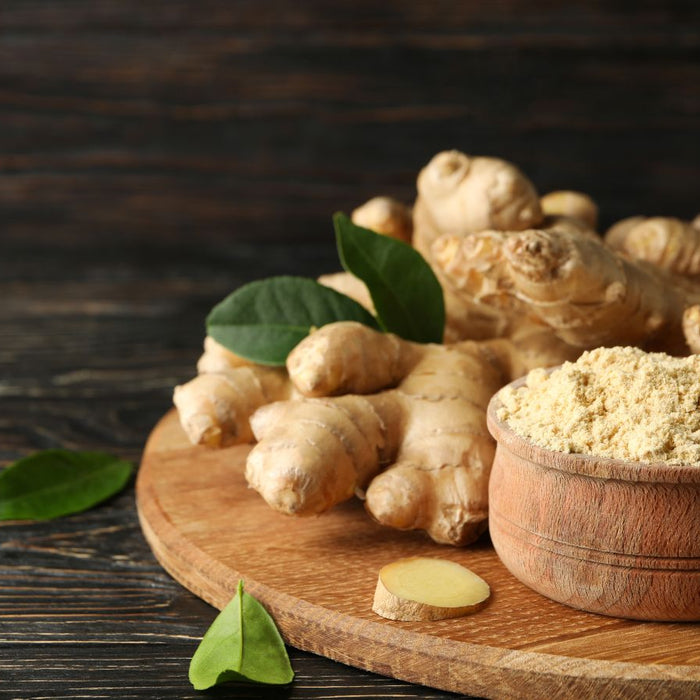 Ground ginger powder in wooden bowl with fresh ginger roots