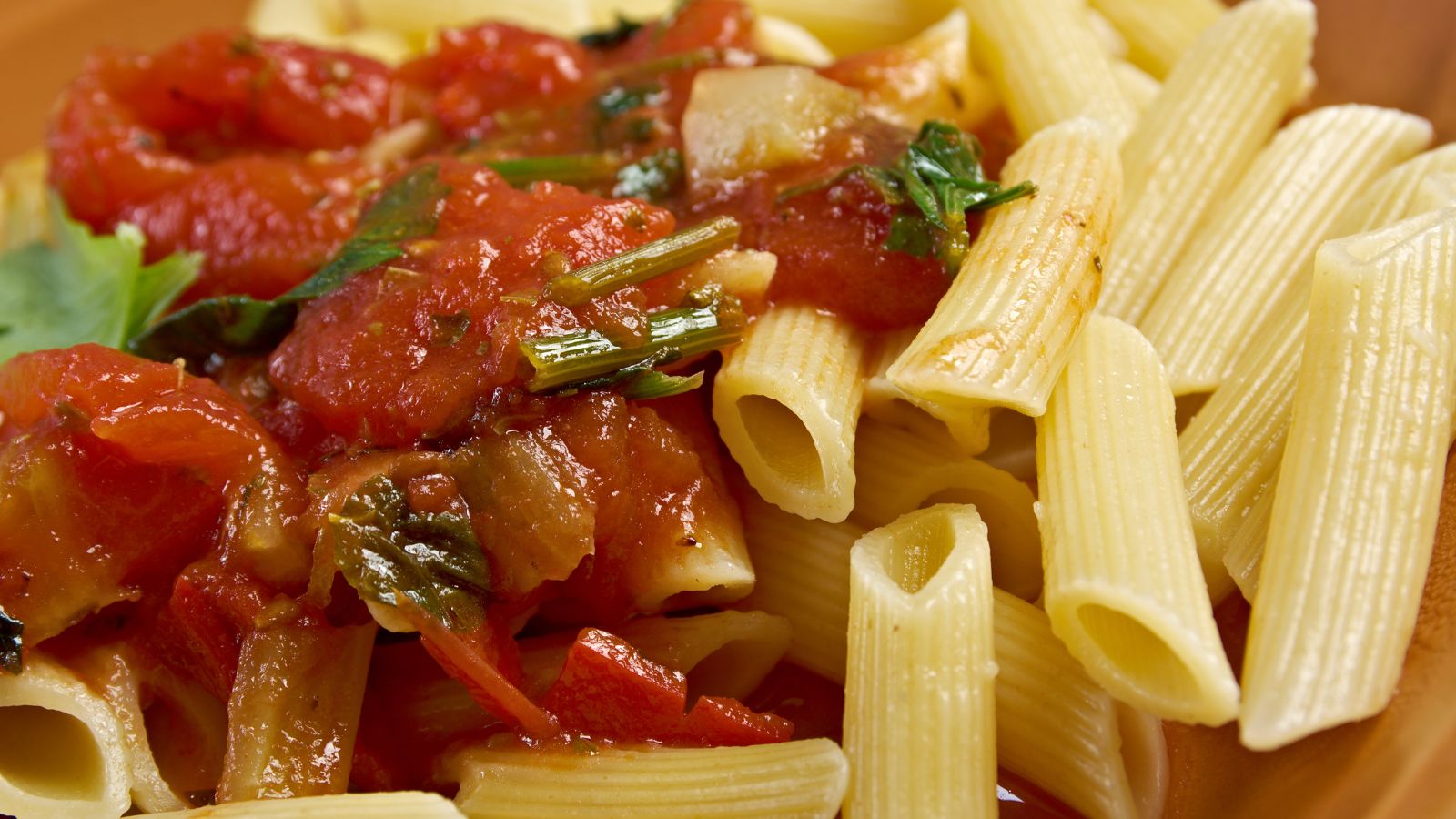 Pasta penne with fresh marinara sauce and herbs on plate