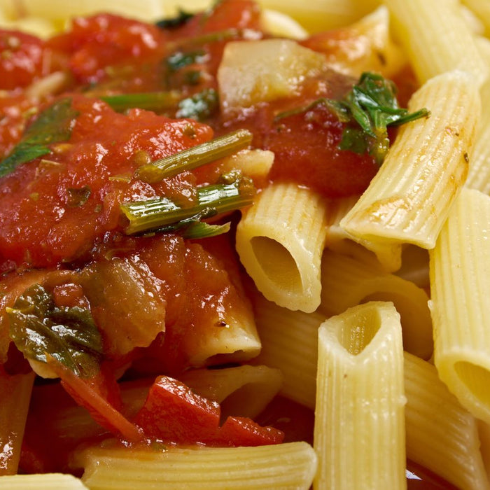 Pasta penne with fresh marinara sauce and herbs on plate