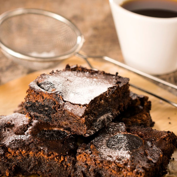 Chocolate brownies served with coffee, dusted with powdered sugar