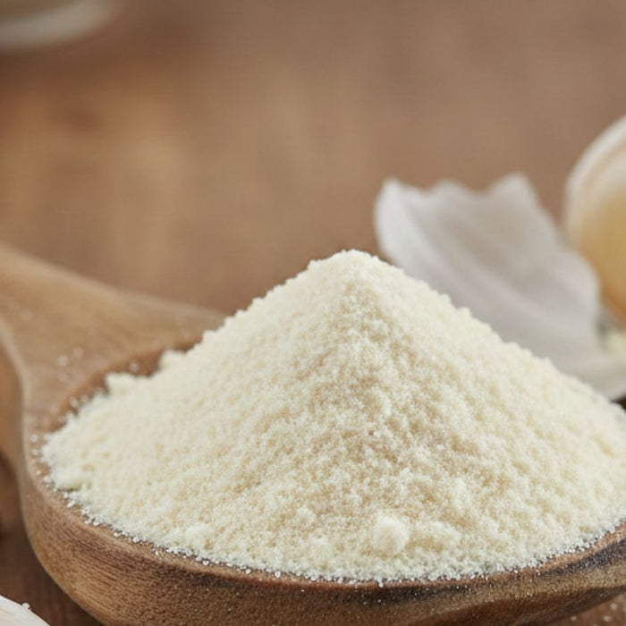 Wooden spoon filled with garlic powder beside fresh garlic cloves