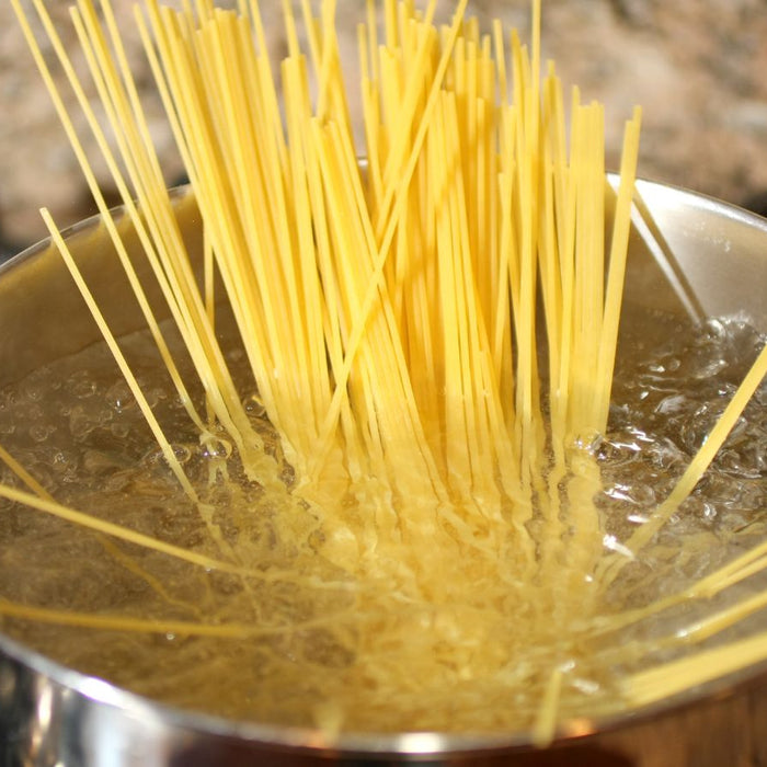 Spaghetti boiling in a pot of water on stovetop.
