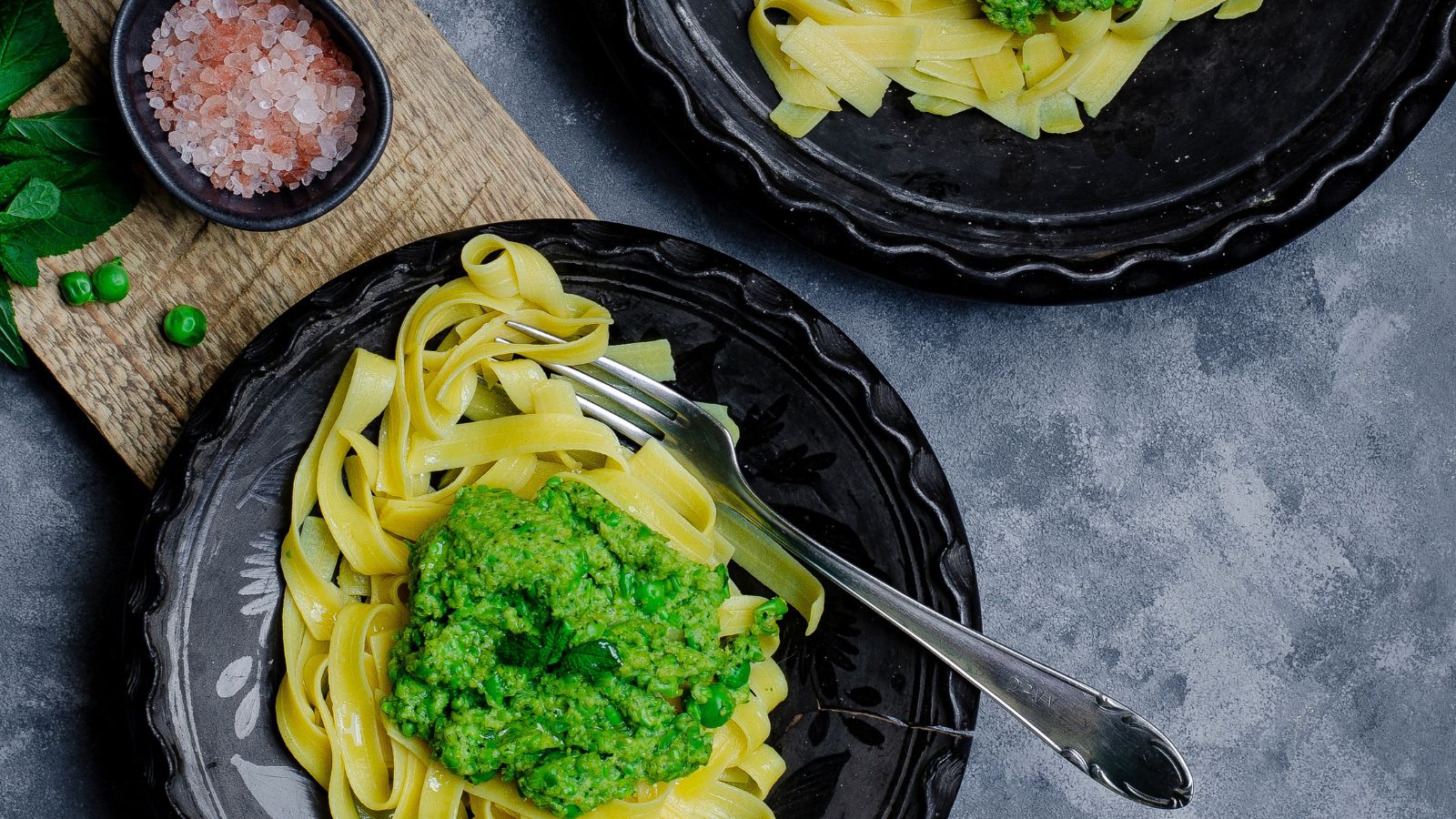 Veggie pasta topped with green pesto sauce on plate