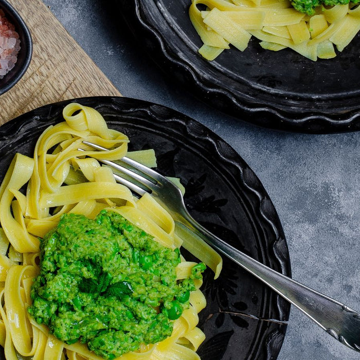 Veggie pasta topped with green pesto sauce on plate