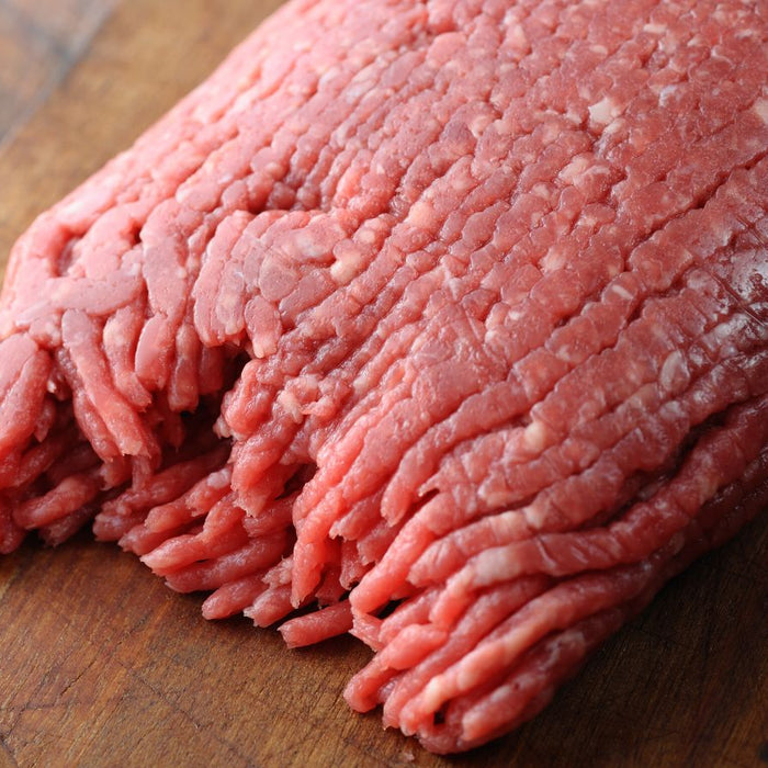 Raw ground beef on a wooden cutting board.