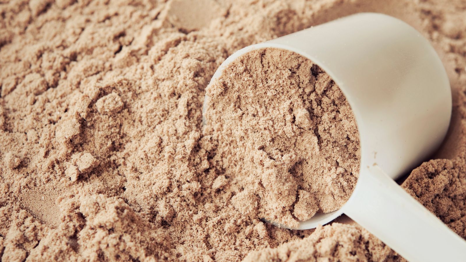 Close-up of a scoop filled with chocolate protein powder on a surface