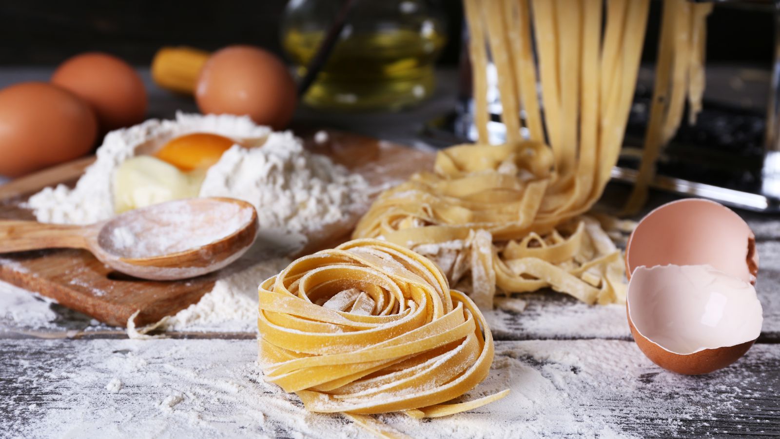Fresh homemade fettuccine pasta being rolled and shaped with flour
