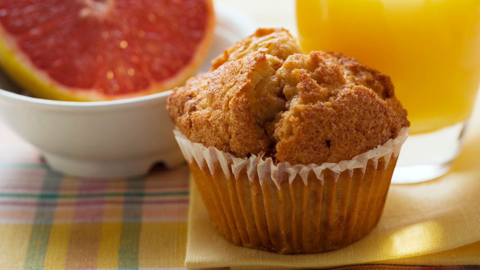 Golden muffin with grapefruit half and glass of orange juice.