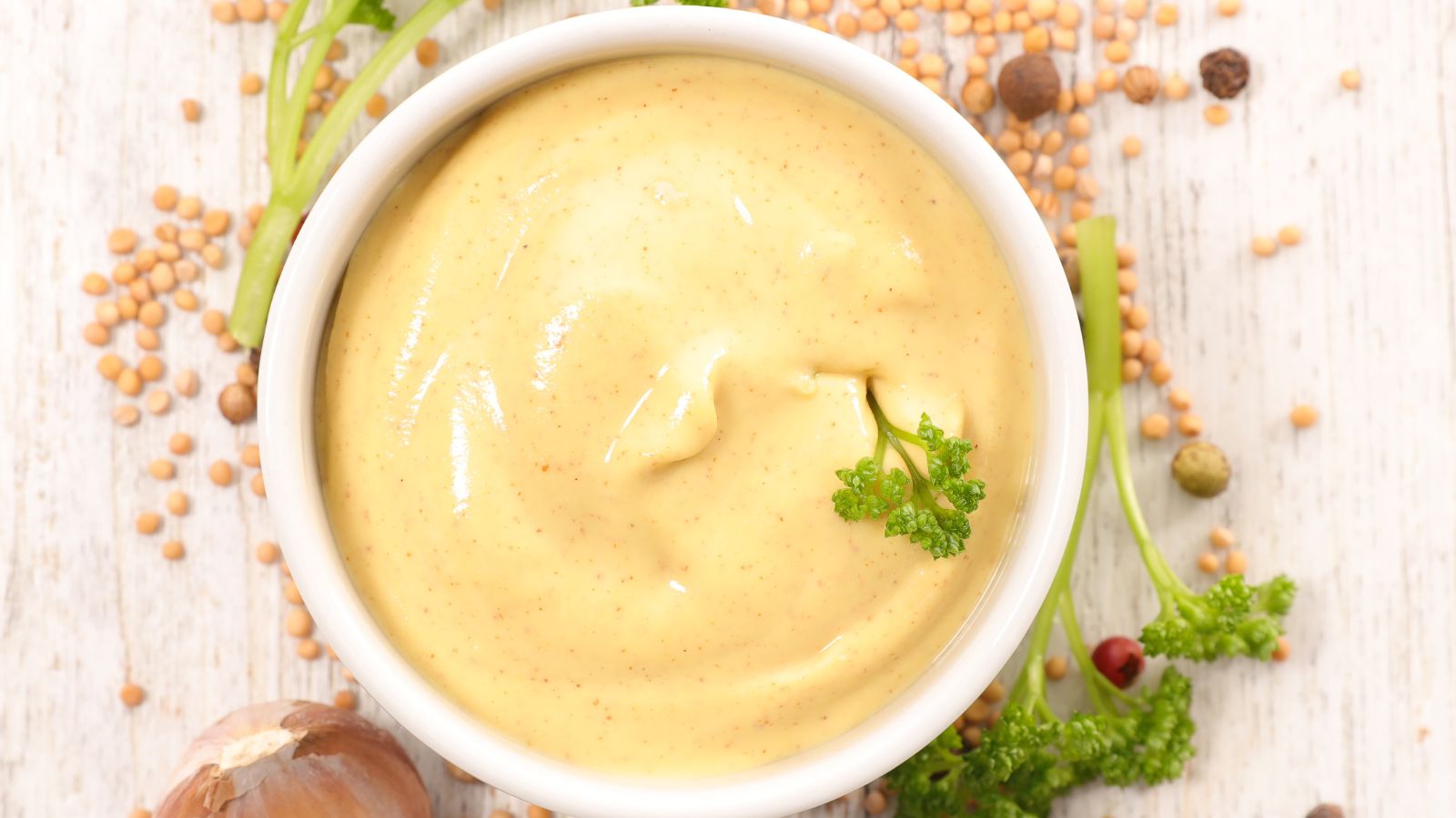Dijon mustard in a bowl with parsley and mustard seeds.