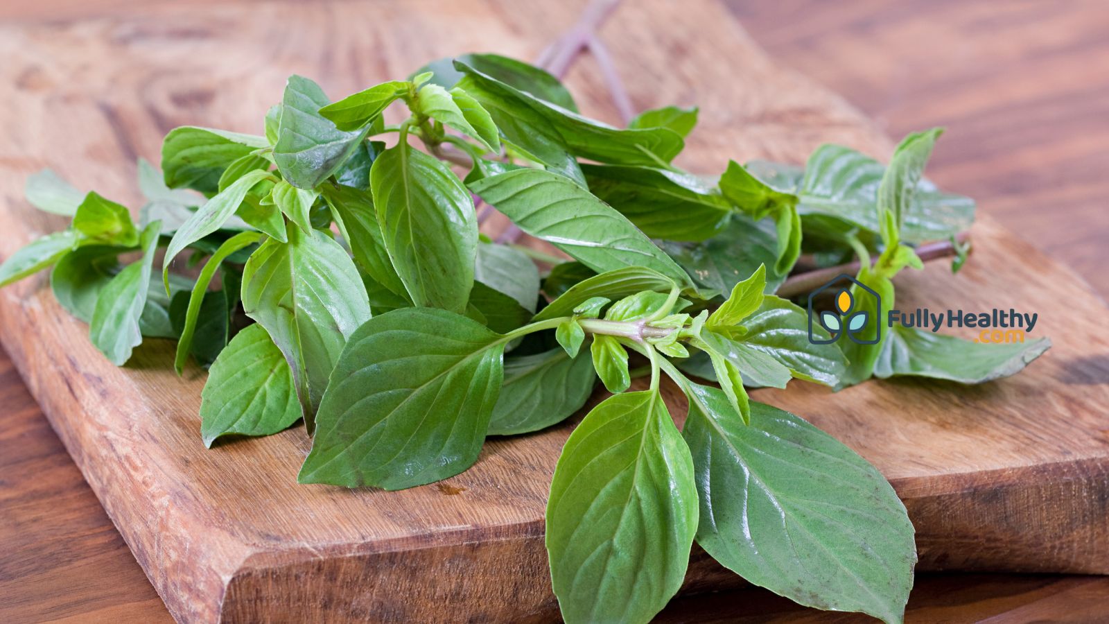 Fresh basil sprigs on wooden cutting board ready for cooking