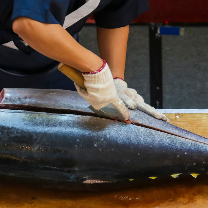 Chef cutting large tuna fish on wooden board for filleting