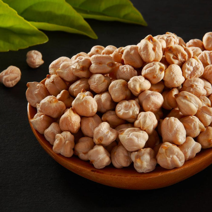 Wooden spoon filled with dried chickpeas on dark background