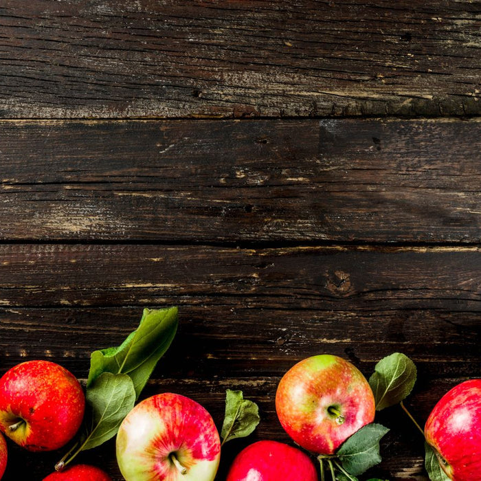 Fresh red apples with leaves on rustic wooden background