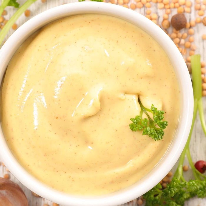 Dijon mustard in a bowl with parsley and mustard seeds.