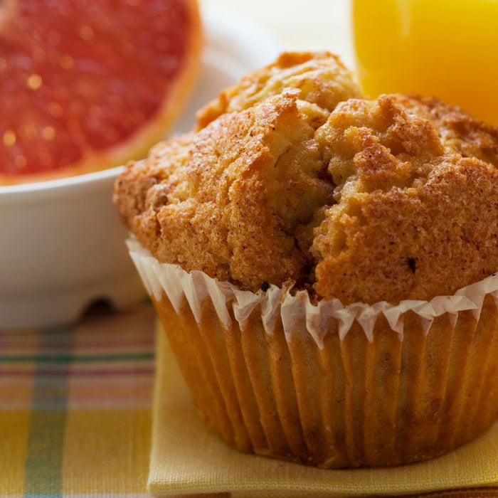 Golden muffin with grapefruit half and glass of orange juice.