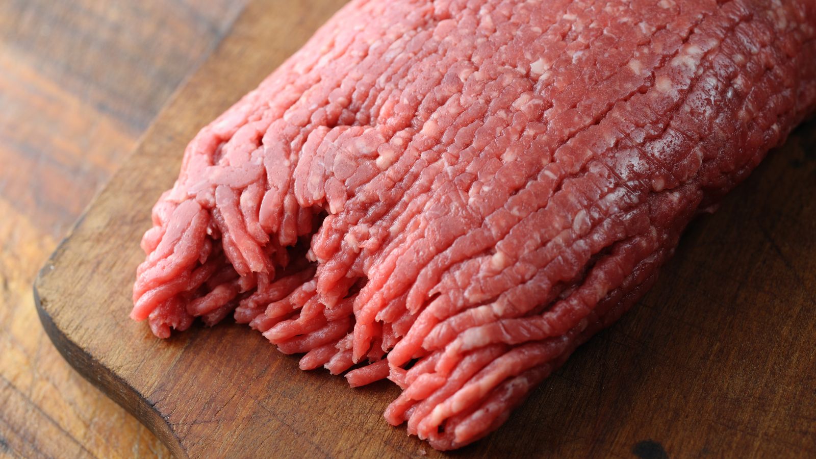 Raw ground beef on a wooden cutting board.