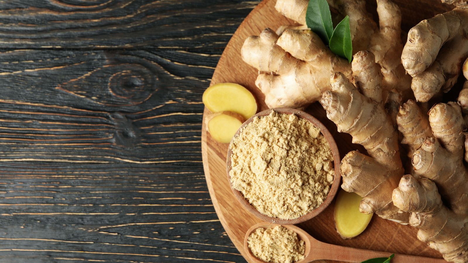 Fresh ginger roots with ground ginger in wooden bowl and spoon