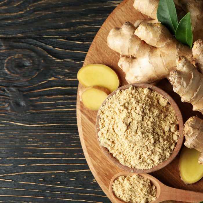 Fresh ginger roots with ground ginger in wooden bowl and spoon